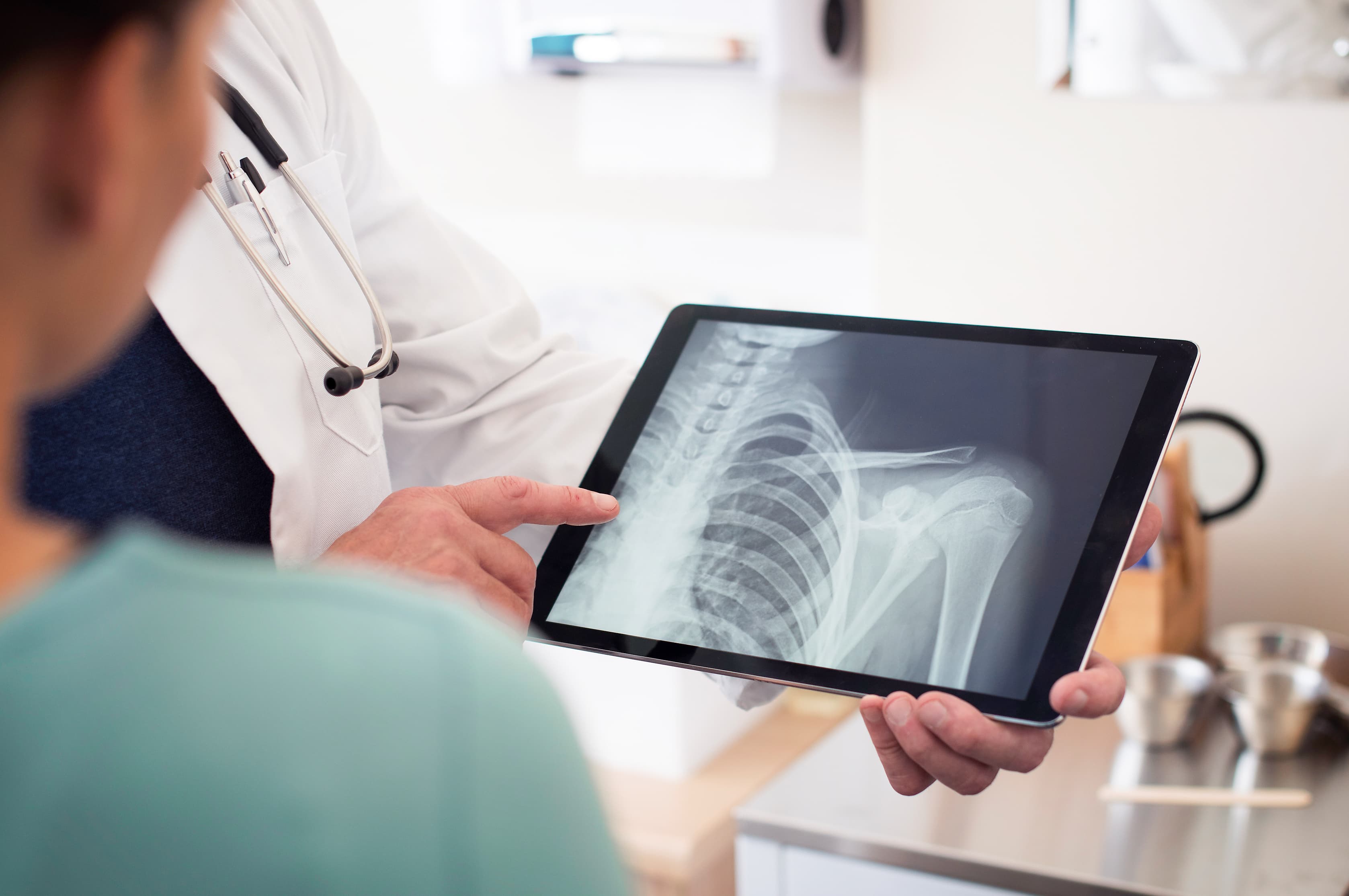 Un médecin montre une radiographie sur tablette à son patient — accès numérique sécurisé aux examens médicaux avec Agora Care